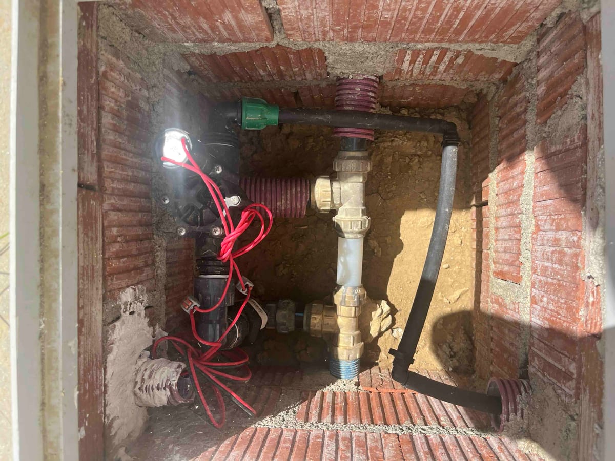 The 24 V valve in its underground brick chamber, wired up and plumbed into the drip line